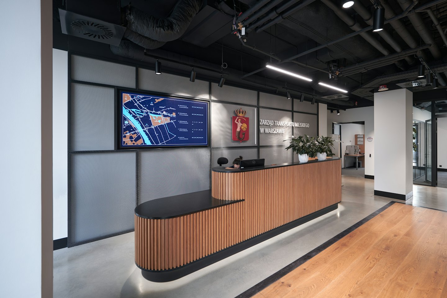 Recepcionista en un escritorio moderno con una pantalla de mapa de la ciudad.